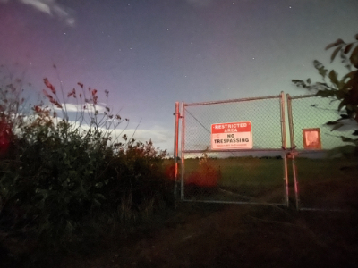 Big fence with a sign that reads 'restricted area' with a pink and green sky.