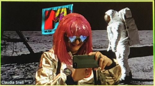 Me taking a photo of my screen during the party and laughing because it was ridiculous. My Zoom background is the classic MTV 'moonman' and I'm dressed like an astronaut with light-up glasses and hot pink wig. 